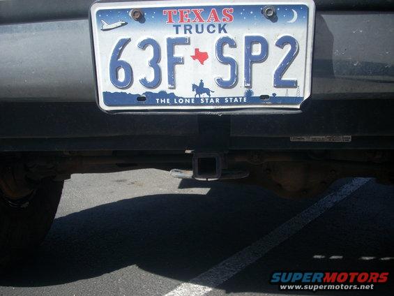 Texas license plate on a vehicle's rear bumper with a trailer hitch