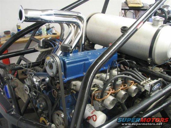 Engine with chrome headers, dual carburetors, and a Ford logo