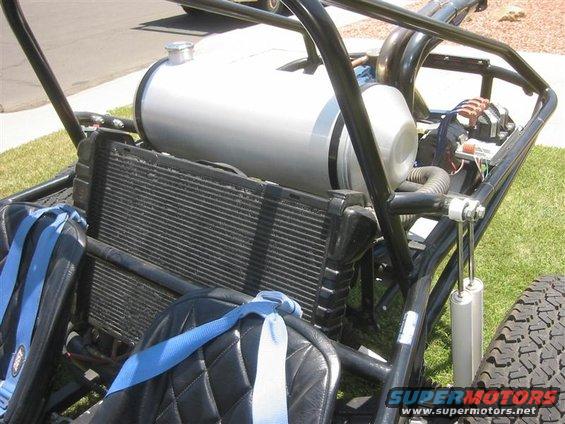 Sand rail buggy interior showing fuel tank, radiator, seats with blue harnesses, and roll cage. "SUPERMOTORS www.supermotors.net" logo in lower right