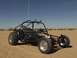 1970 Sand Rail High Jumper - A black sand rail buggy is parked in a sandy desert environment under a clear blue sky.