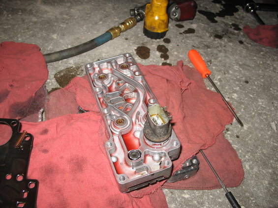 Transmission valve body with red fluid, air hose, and tools