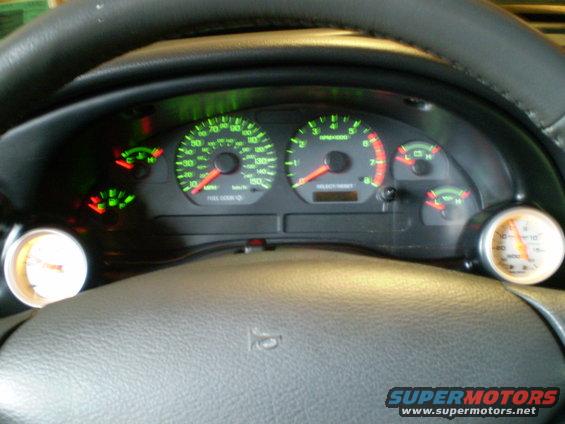 2002 Ford Mustang dashboard with speedometer, tachometer, fuel gauge, and two aftermarket gauges
