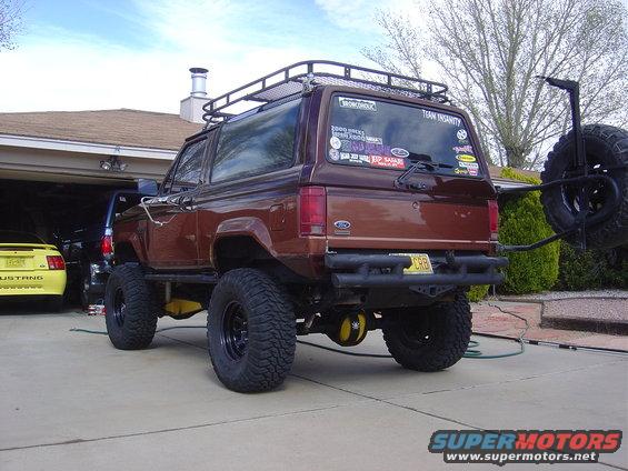 Brown Ford Bronco II with roof rack and spare tire carrier, lifted with large tires
