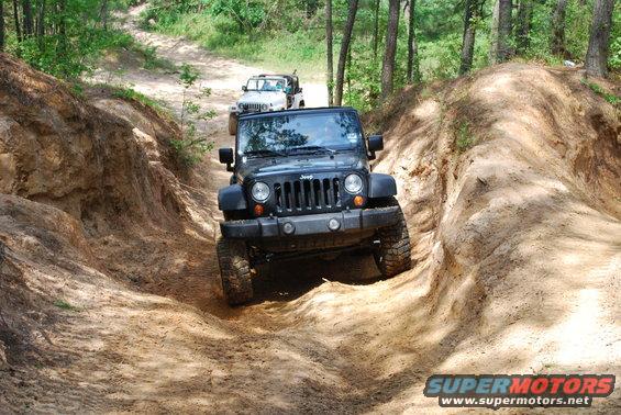 Black 2008 Jeep Wrangler and a white Jeep Wrangler on a dirt trail