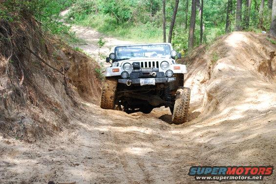 2008 Jeep Wrangler climbing a steep dirt path with trees on either side