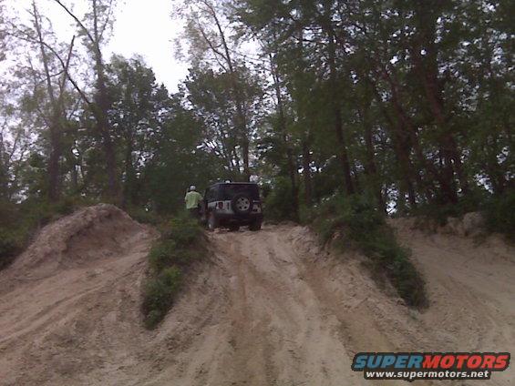 Rear view of black 2007 Jeep Wrangler on a sandy hill with trees