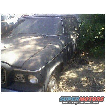 Dusty old car parked outdoors, partially obscured by trees