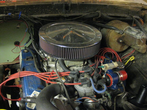 Ford V8 engine block with blue valve covers, chrome air cleaner, and red spark plug wires