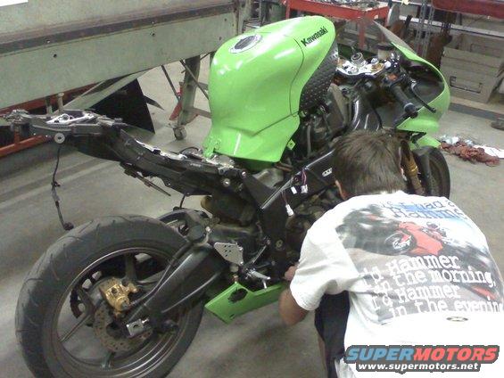 Green 2005 Kawasaki Ninja R motorcycle with fairings removed, being worked on by a person. Kawasaki logo visible on the tank