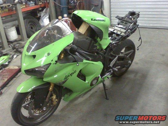 Green Kawasaki Ninja motorcycle with fairing damage, missing rear seat section, and visible engine components