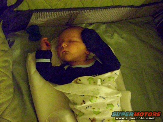 Baby sleeping in a crib, wrapped in a blanket with cartoon animals