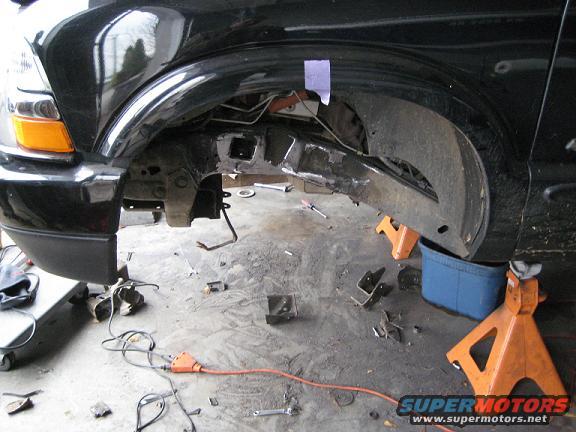 2004 Chevrolet Blazer front wheel well area with suspension disassembled, supported by jack stands