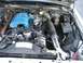 1985 Ford Crown Victoria LTD - The engine bay of a 1985 Ford Crown Victoria LTD is visible, with a blue intake manifold and various engine components.