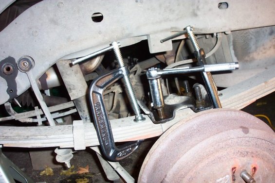 Vehicle leaf spring with C-clamps and a socket wrench tool attached to suspension