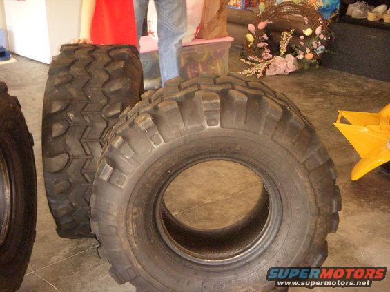 Three large off-road tires on a concrete floor.