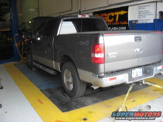 Rear view of a dark gray Ford F-150 XTR pickup truck on a dynamometer. The truck has a two-tone paint scheme with a silver lower body