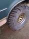 1990 Ford Bronco - A close-up view of a vehicle's fender flare and a large, aggressive off-road tire mounted on a gold rim.