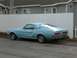 1967 Ford Mustang - A light blue 1967 Ford Mustang coupe is parked on the side of a street, with a white fence and house in the background.