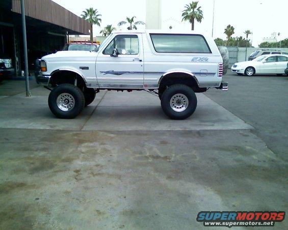lifted white Ford Bronco with custom wheels and tires, parked outside