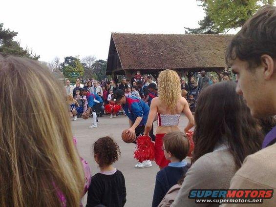 Crowd watching a basketball performance near a wooden pavilion