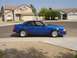 1989 Ford Mustang - A blue coupe with a spoiler and racing seats is parked in front of a house.