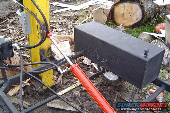 Black hydraulic log splitter with red cylinder and yellow support beam, outdoors