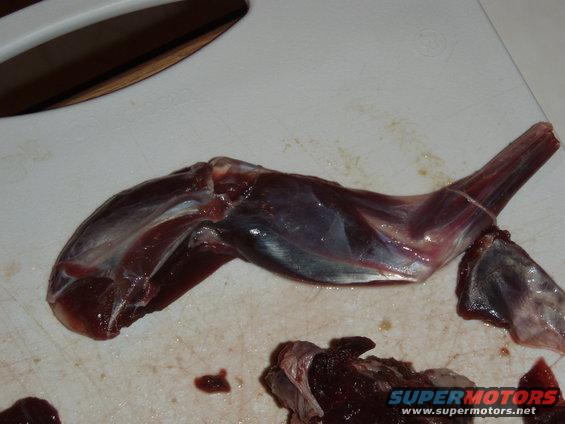 Raw meat leg on a cutting board with text 'SUPERMOTORS www.supermotors.net'