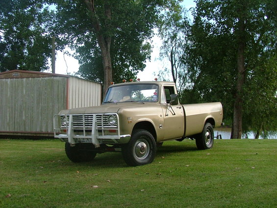 Tan International pickup truck parked on grass near a shed and a body of water
