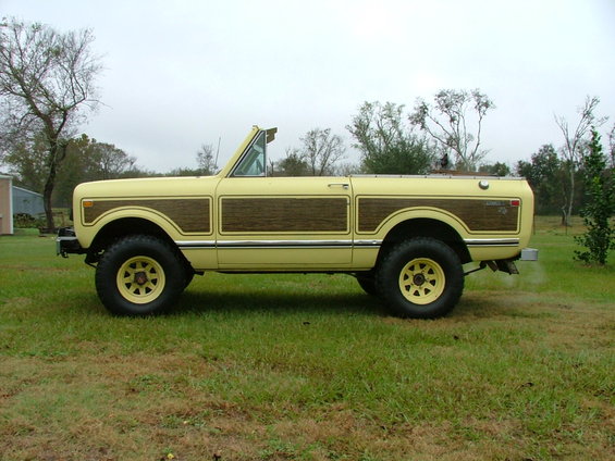 Yellow 1975 International Scout II with wood paneling, parked on grass