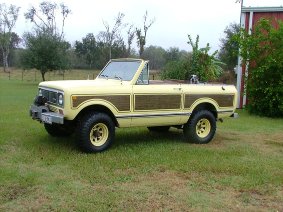Yellow 1975 International Scout II convertible with wood paneling parked on grass