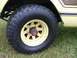 1975 International Scout II - Close-up of a vehicle's wheel and lower body panel, showing off-road tire and wood grain trim.
