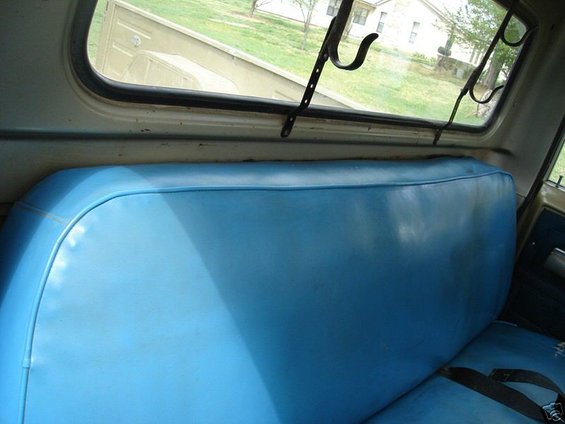 Blue vinyl bench seat and rear window view of a residential area