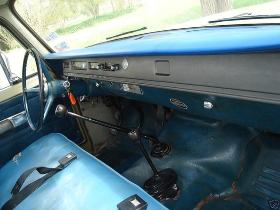 Interior of a vehicle with blue seats and dashboard, a steering wheel and gear shifter