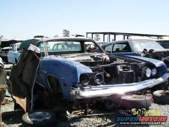 1972 Ford Ranchero front end in junkyard, hood open, missing parts