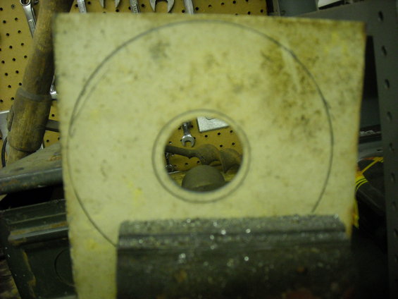 Square material with drawn circles, held in a vise, with tools in background