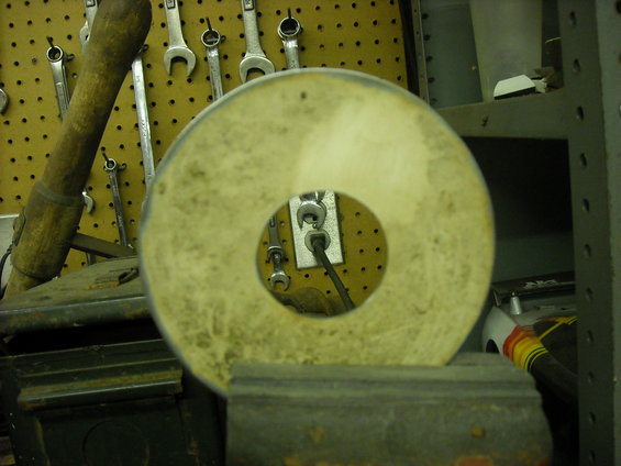 Workbench with tools on pegboard, a grinding wheel in foreground, and a white toy car in background