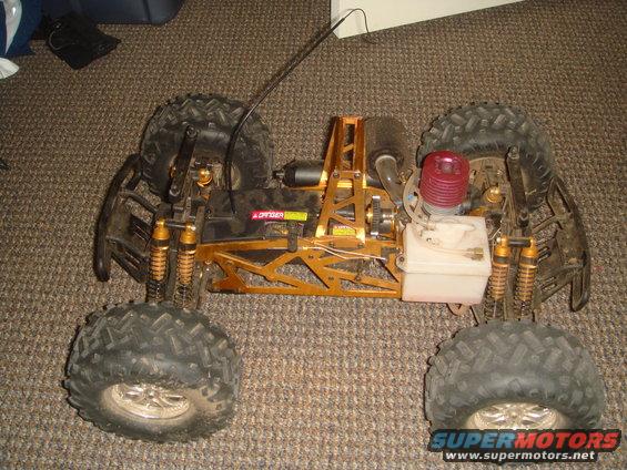 Remote control monster truck with gold frame, red engine, and large tires on carpet