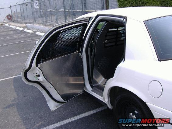 1999 Ford Crown Victoria interior with open doors, metal cages, and partition