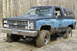 1995 Ford Bronco - This Chevrolet K5 Blazer, likely from the 1980s, is stuck deep in mud on a wooded trail.