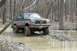 1995 Ford Bronco - Ford Bronco navigating a challenging muddy terrain in a wooded area.