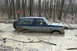 1995 Ford Bronco - A Ford Bronco navigates a muddy off-road course, partially submerged in water and mud.
