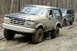 1995 Ford Bronco - A muddy 1995 Ford Bronco navigates an off-road trail, followed closely by a Jeep Grand Cherokee.