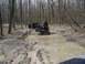 1991 Ford Bronco - Two SUVs are stuck in a muddy forest road, with people around them.