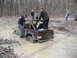 1991 Ford Bronco - People gather around a Jeep Wrangler stuck in a muddy off-road trail.