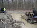 1991 Ford Bronco - Two off-road vehicles navigate a muddy trail, with one Jeep deeply mired in the muck.