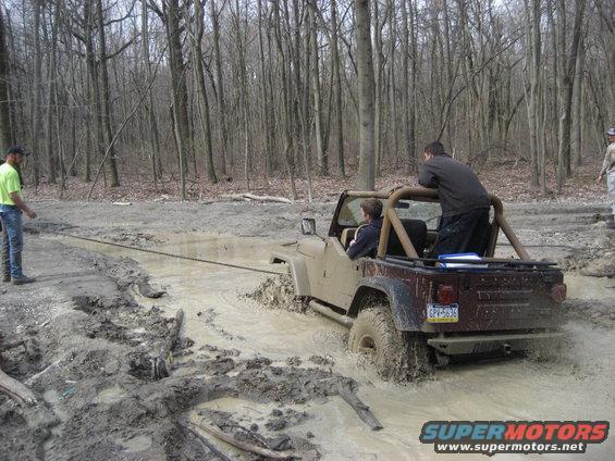 Tan Jeep Wrangler stuck in mud, rear view