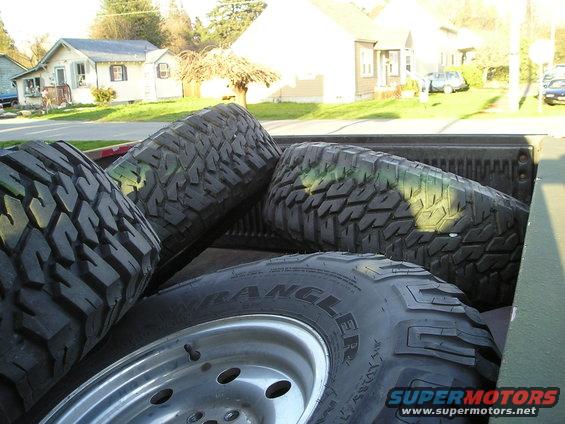 Tires piled in the bed of a pickup truck. One tire has 'WRANGLER' visible