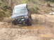 1989 Ford Bronco - Modified 1989 Ford Bronco tackles a challenging muddy obstacle on an off-road trail.