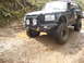 1989 Ford Bronco - This modified SUV navigates a challenging off-road path with deep mud and uneven terrain.