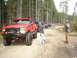 1989 Ford Bronco - A convoy of off-road vehicles are lined up on a dirt road in a forest.